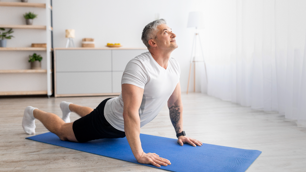 Man in an upward dog yoga position on a blue yoga mat