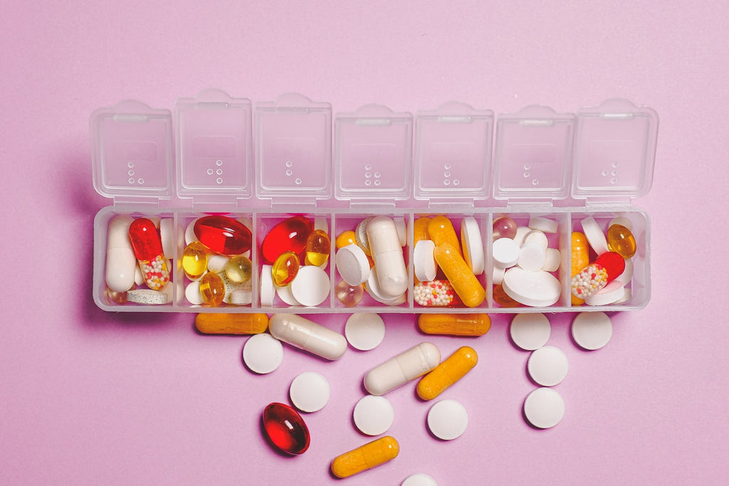 A pill organizer is overflowing with a variety of multicolored pills.