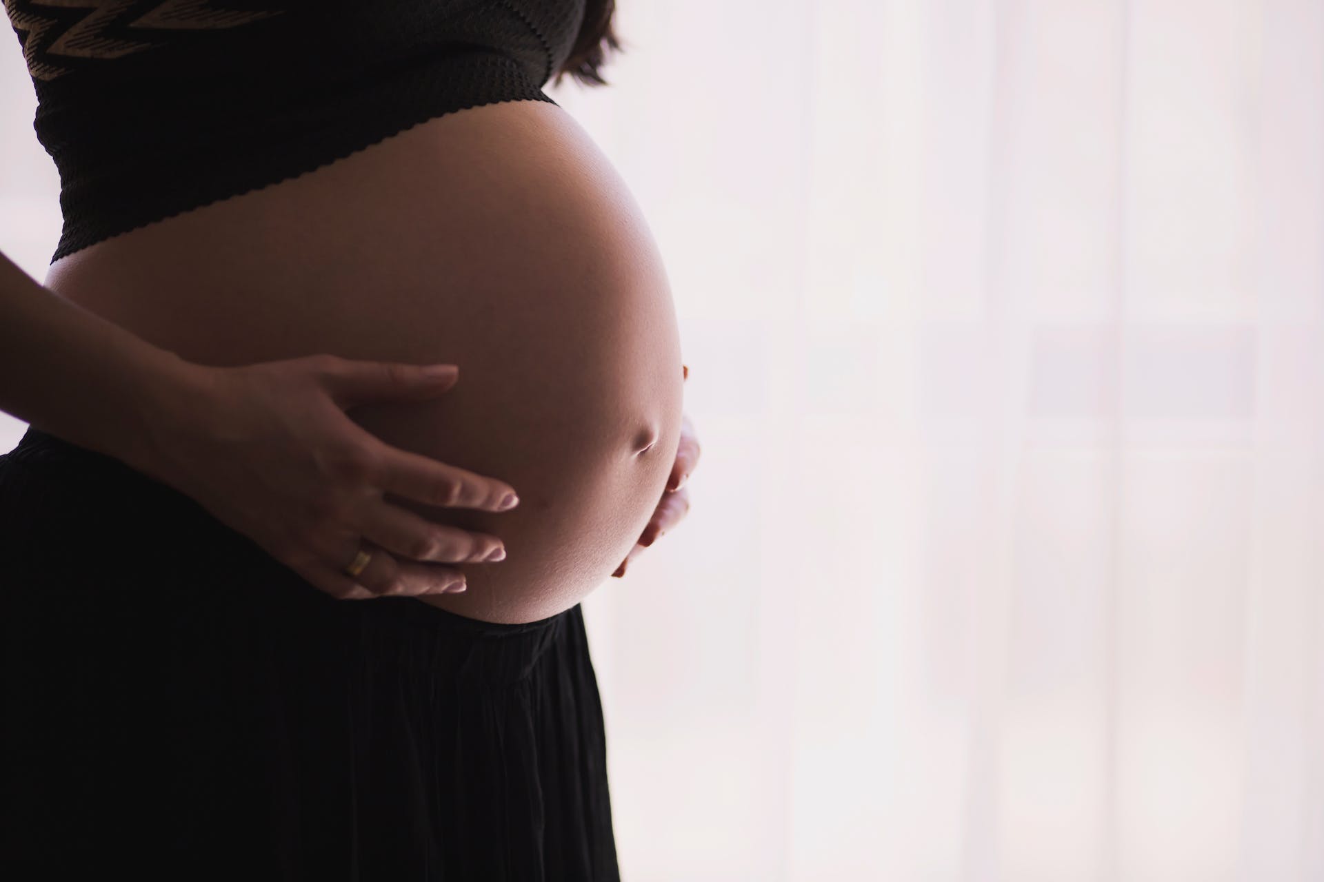 A person holds their pregnant stomach.