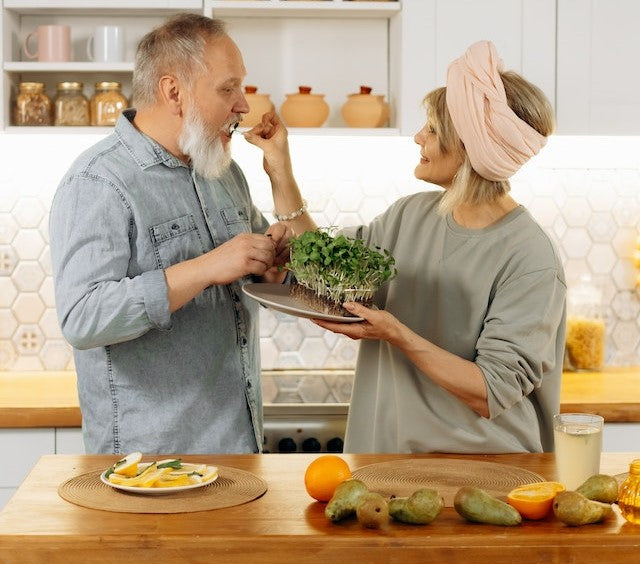 A couple happily prepares a healthy meal together in their kitchen.