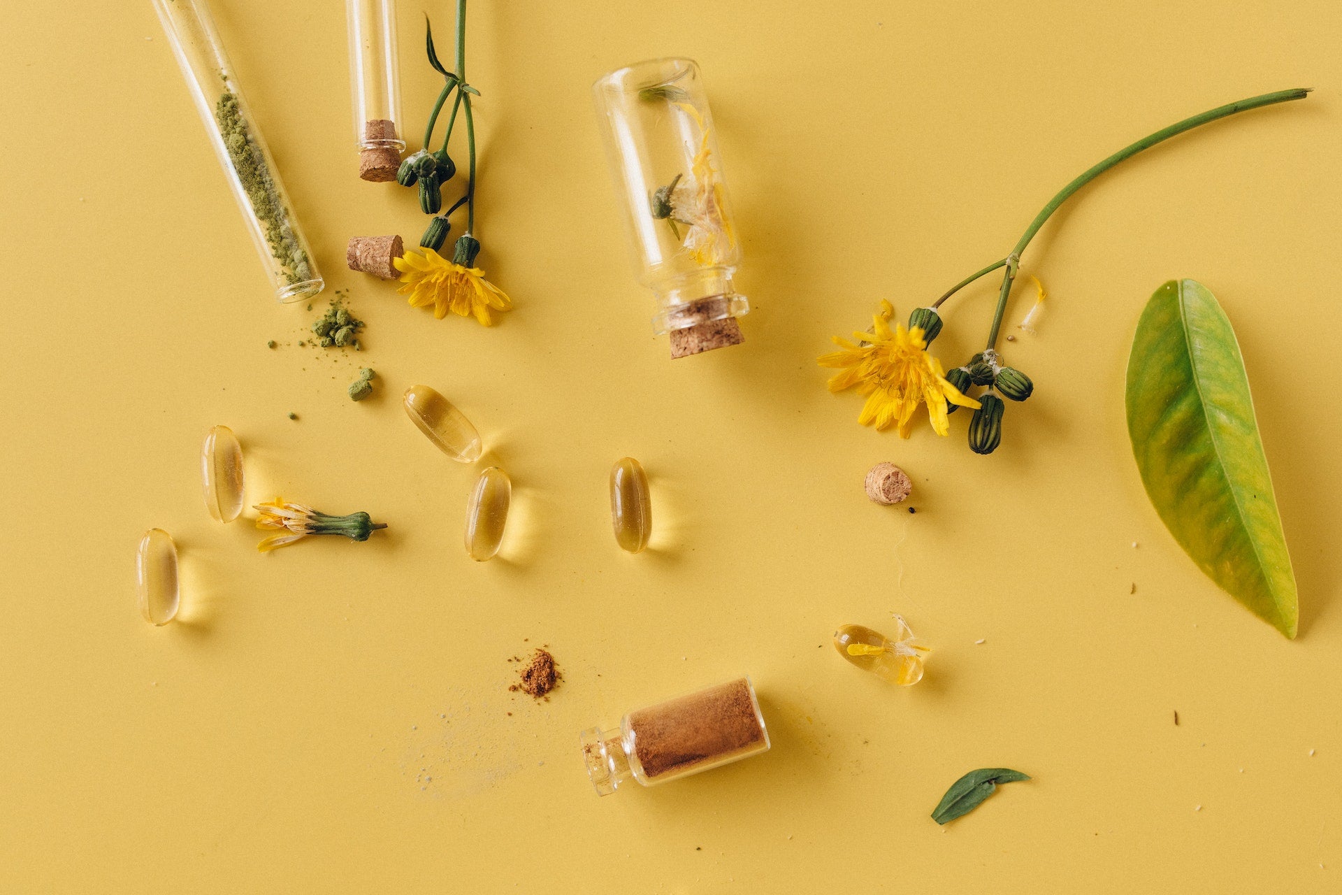 A mix of plants, pills, and natural powders on a yellow background.