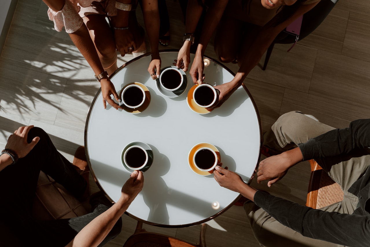 A bird's eye view of people gathered around a table with coffee mugs.