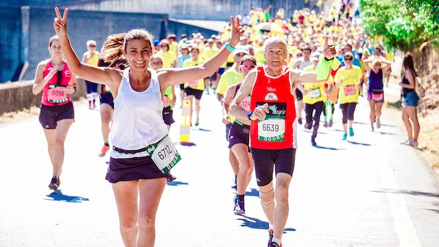 A runner lifts her hands in celebration as she competes in a marathon.