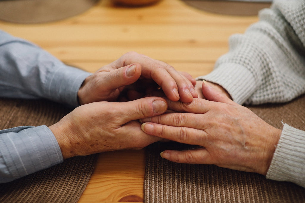 Two people hold hands across a table.