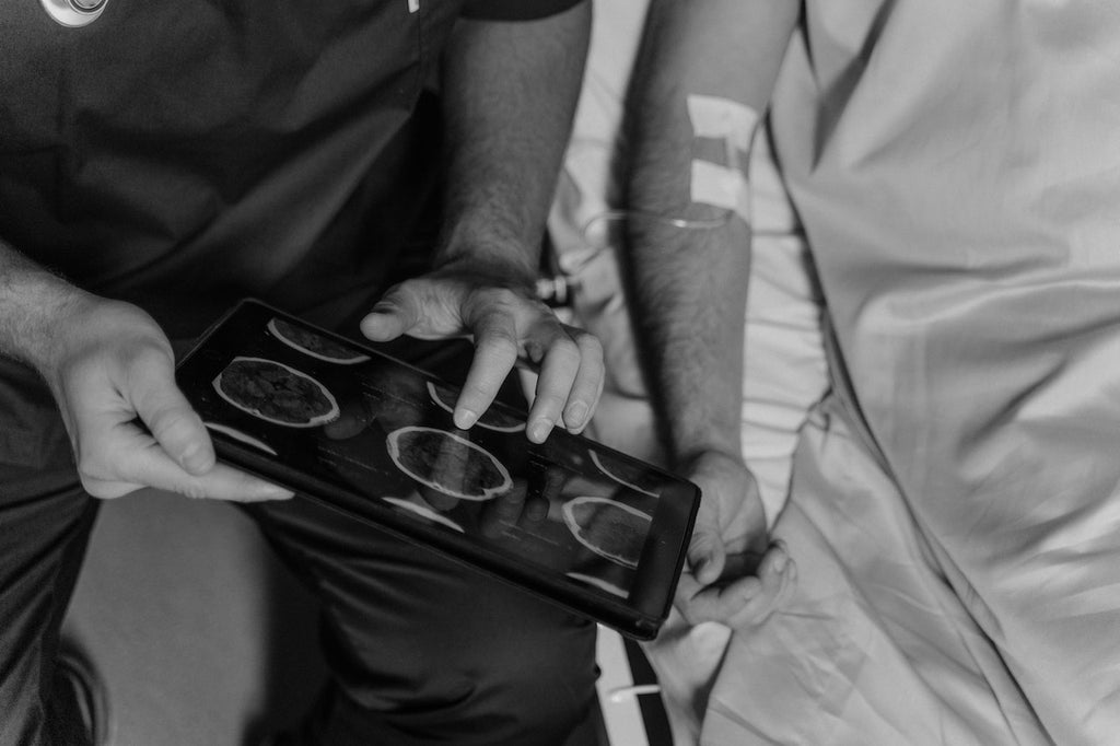 A doctor shows a brain scan to a patient in a hospital bed.