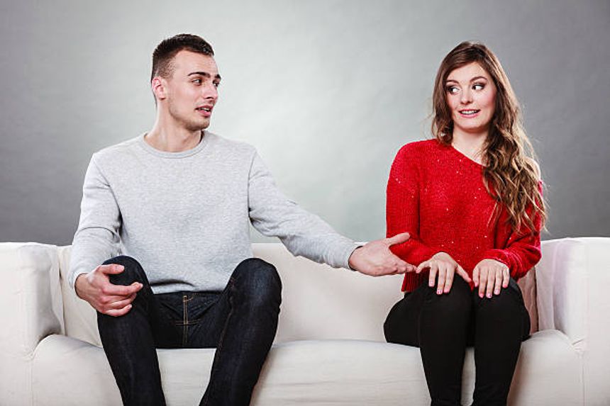 A shy woman and a man sitting on a sofa together. First date. Attractive and handsome girl who meets dates and tries to talk. Man offering a hand to the woman.