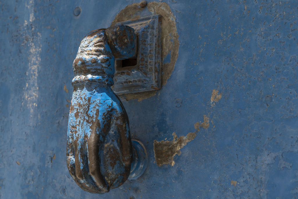 Moorish inspired Hand of Fatima door knocker on blue door in the Algarve in southern Portugal