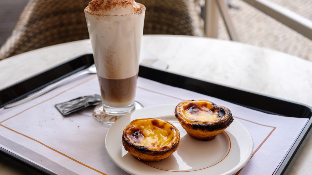 Pastel de nata with a latte on cafe table in Portugal