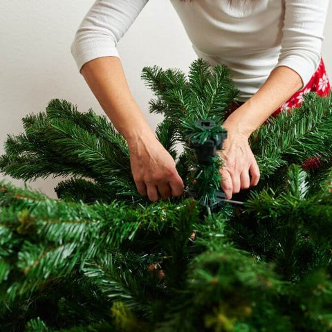 Woman Fluffing Artificial Christmas Tree Branches