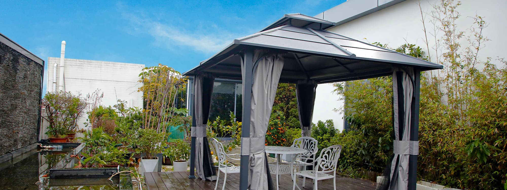 A hardtop gazebo installed on a wooden deck in the front porch