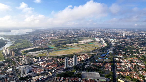 An aerial image of Interlagos race track in São Paulo, taken from the North looking Southwards at across the track. The image shows the extent to which Interlagos has been surrounded by buildings and all sides. The buildings are a mixture of residential and industrial. Billings reservoir can be seen beyond the circuit and buildings.