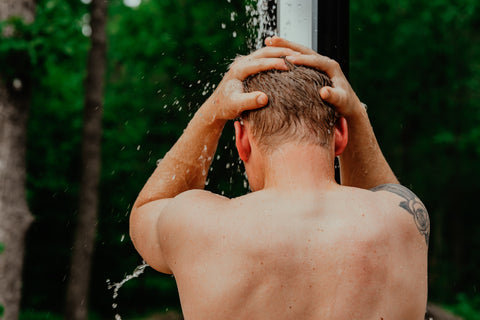 Man showering outside with hands on head