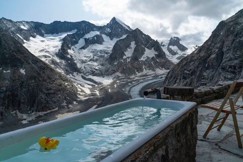 Rubber duck in outdoor ice bath against mountain backdrop