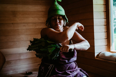 Woman sitting in sauna with leaves