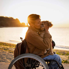Disabled man in wheelchair hugging his dog.