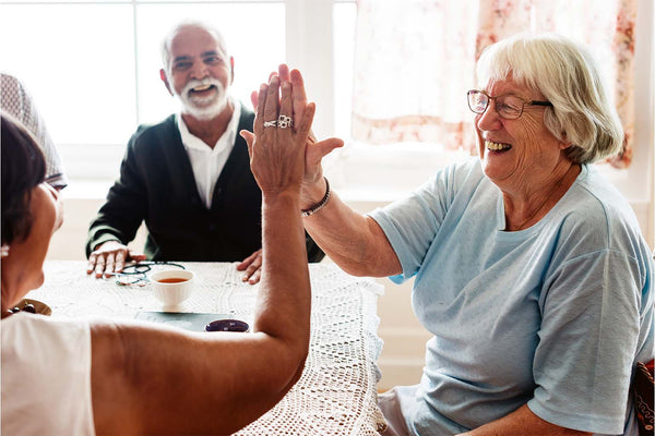 Elderly woman giving a high five while smiling.