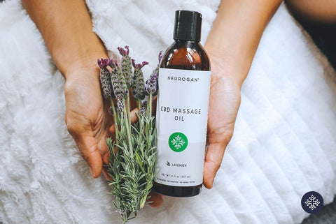 Photo of Neurogan CBD Massage Oil and a bundle of lavender flowers being held in hands.