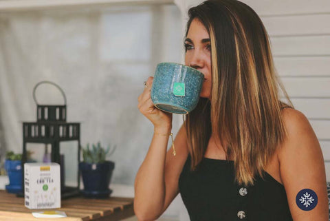 Woman with Medium Length Dark Brown Hair Drinks CBD Tea From an Aqua Blue Ceramic Mug