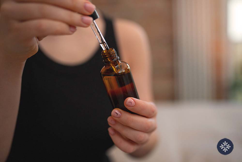 Woman holding a dropper and jar of CBD tincture