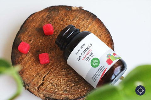 A bottle of CBD Gummies spread on a wooden piece next to a gummies jar