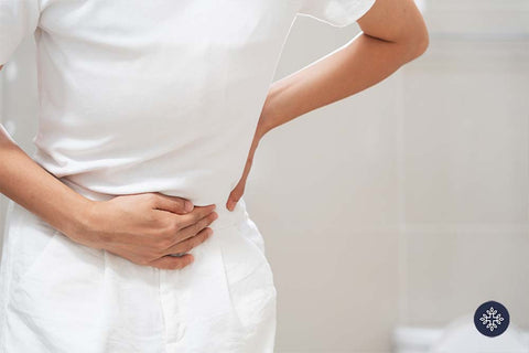 Woman holding her stomach standing in a restroom