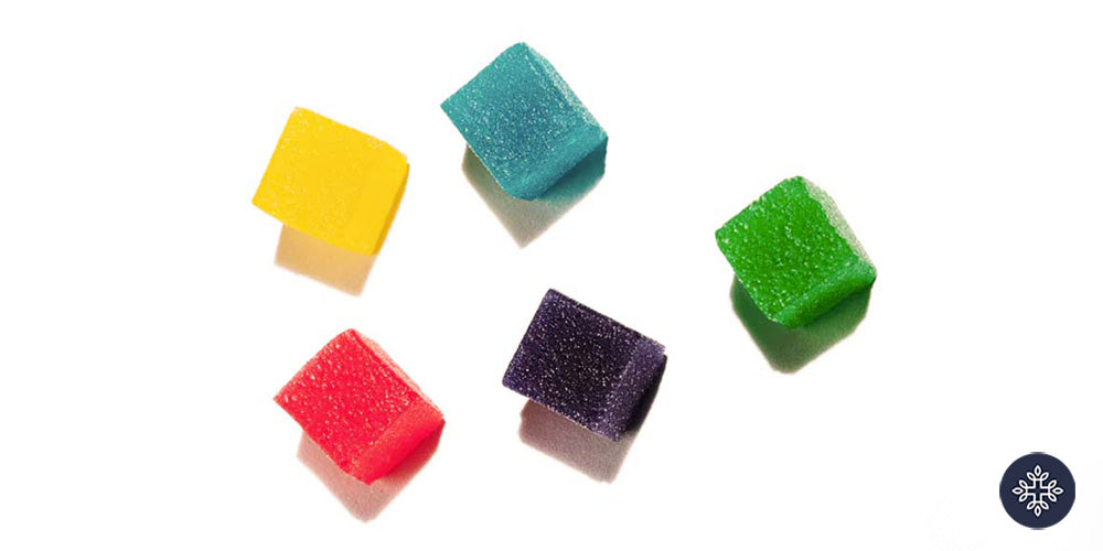 5 different colored THC Gummy squares on a white surface