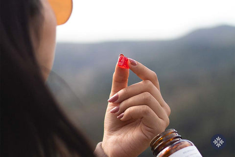 Woman holding one red CBD gummy