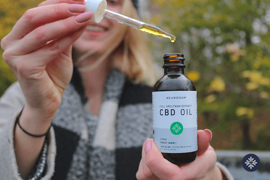 a woman holding a tincture of Neurogan CBD oil