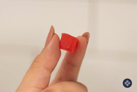 Woman hand holding one red CBD gummy