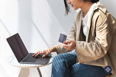 Woman sitting in front of a table doing online shopping with her card on hand