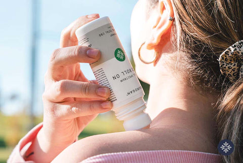 Woman applying to her left shoulder Neurogan CBD roll up.