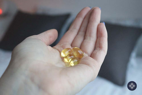 Photo of a hand holding golden colored CBD softgels.