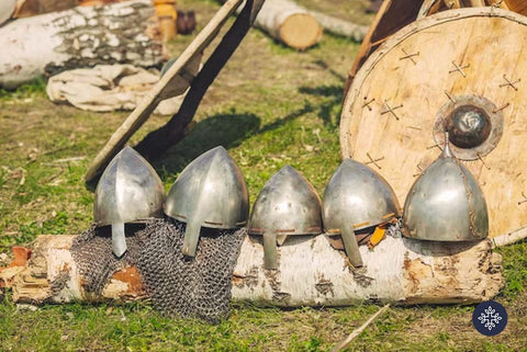 Viking helmets lined up on a log outside in the sun