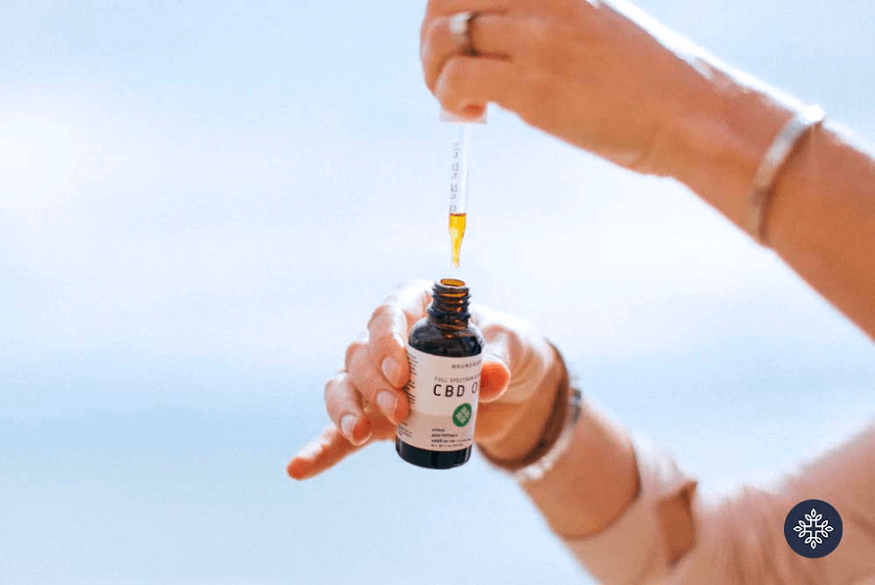 Hands holding Neurogan CBD oil tincture in the sun