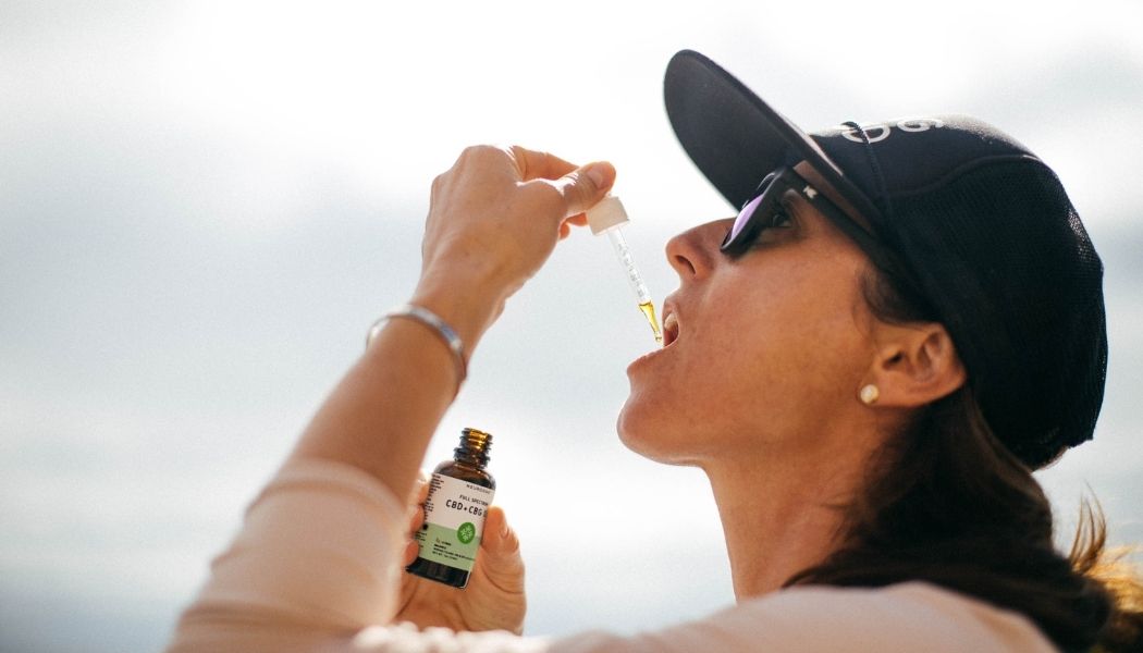 WOMAN placing CBD CBG balance Oil under her tongue