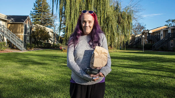 meals on wheels volunteer smiling while holding bag of food