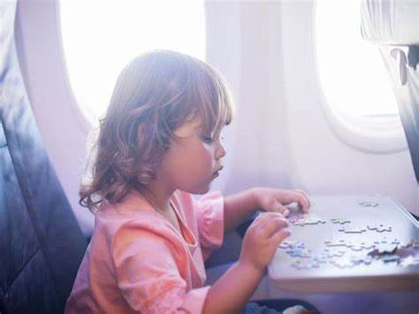 Little girl doing jig saw puzzle on a plane
