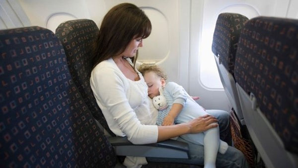 Baby sleeping in mother's arms in plane