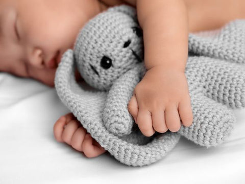 Baby sleeping in hotel bed with bunny