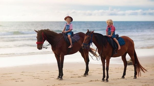 Kids horse riding by the beach