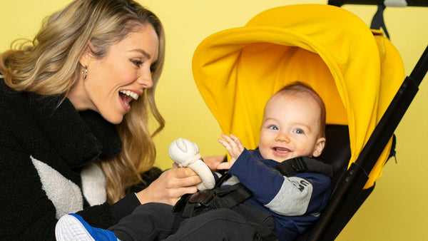 Mom entertaining baby in suitcase stroller