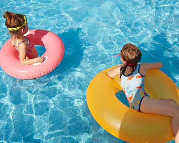 Sisters with inflatable donuts in swimming pool