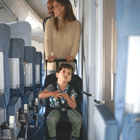 Parents pushing child along plane aisle with TernX Carry On