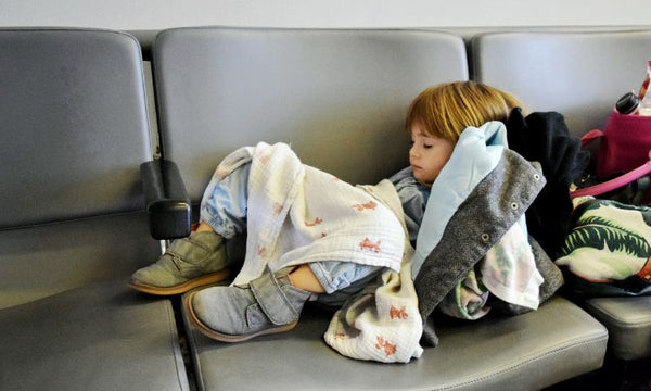 little boy jet lagged and sleeping on seats at airport