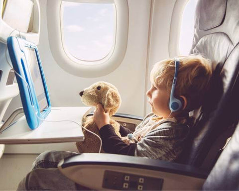 little boy in plane watching ipad with headphones