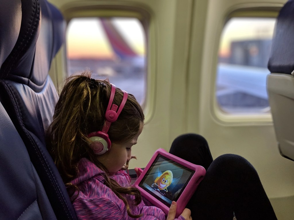 little girl preoccupied with an ipad on the plane
