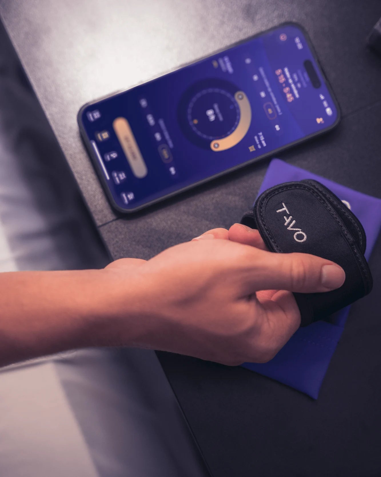 Hand holding a device near a smartphone displaying a circular interface.