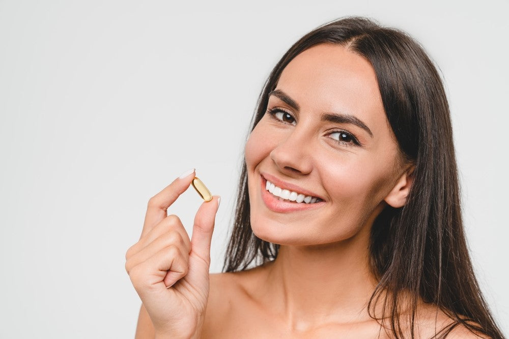 women smiling and holding supplement capsule in hand