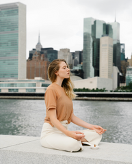 Girl sitting on riverbank in the city meditating