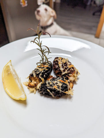 Plated crab stuffed morels with adorable dog in background